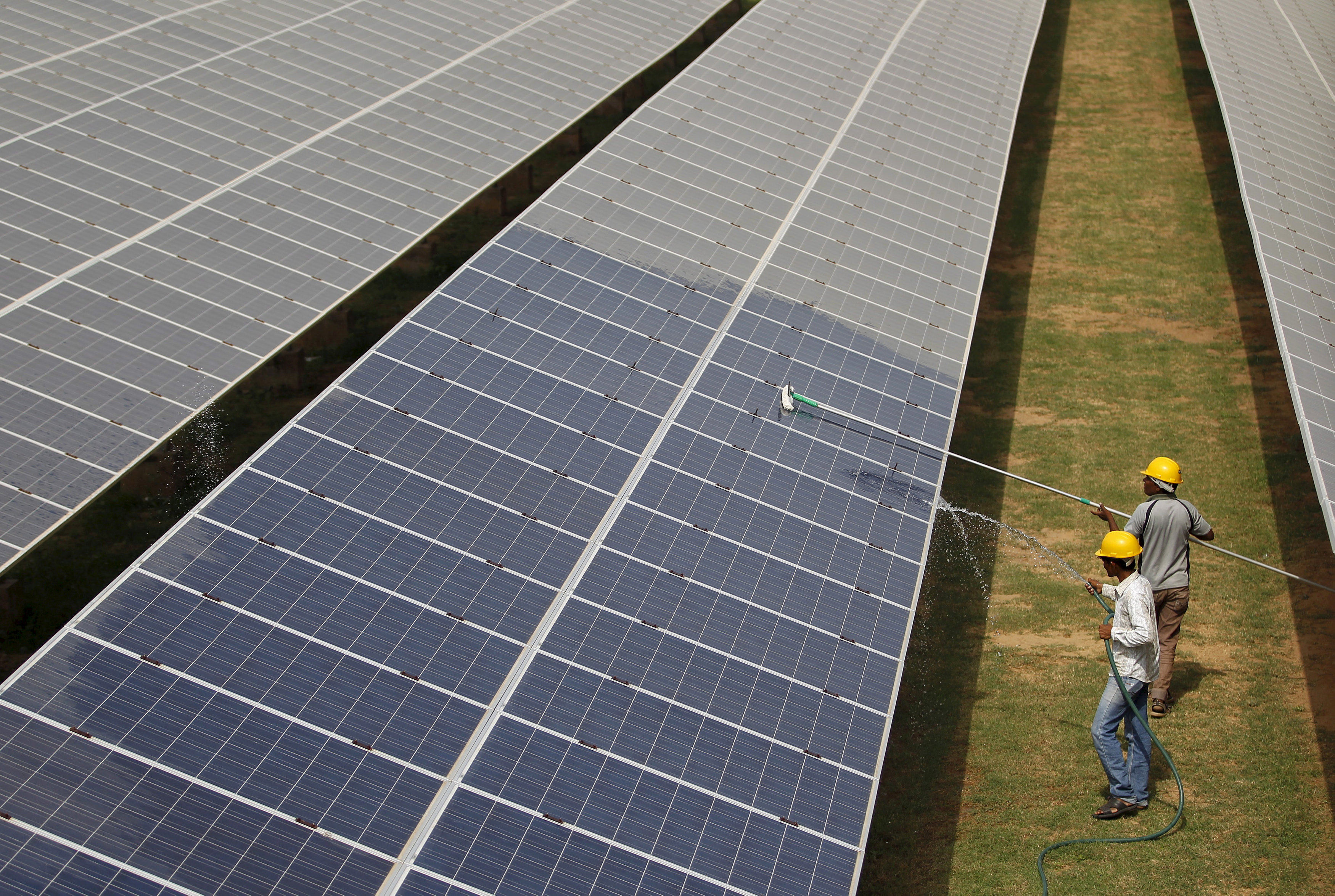 Workers clean photovoltaic panels inside a solar power plant in Gujarat, India. Photo: Reuters